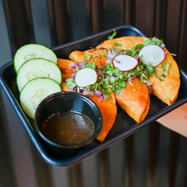 Three Tacos Number Juan birria tacos with radishes, cilantro, onions, cucumbers, and dipping sauce.