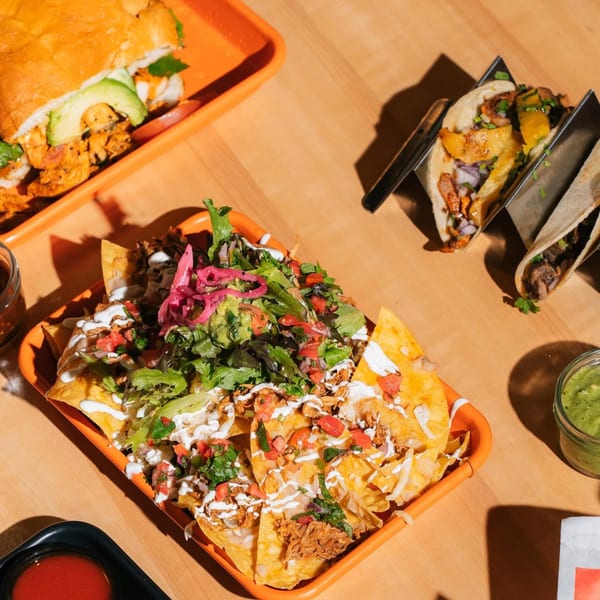Overhead view of Tacos Number Juan's nachos, torta, and tacos on a wooden table.